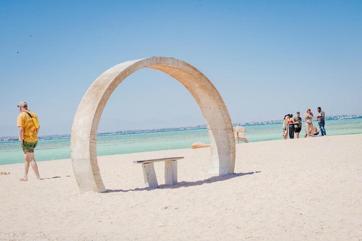 un arco di legno su una spiaggia con una panchina