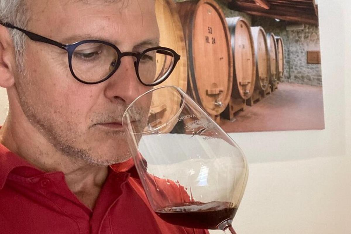 un uomo con gli occhiali che beve un bicchiere di vino