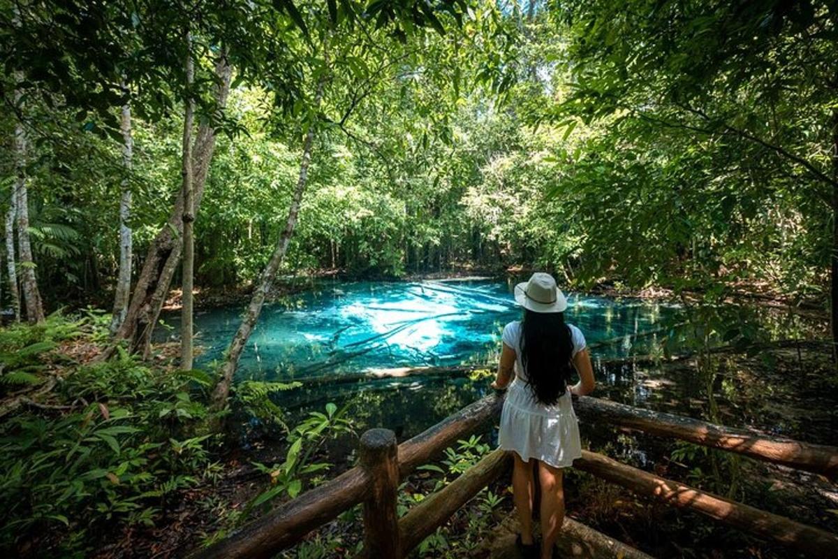 một người phụ nữ đội mũ đứng trên hàng rào gần sông