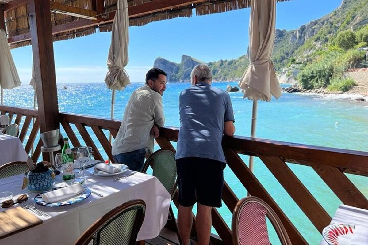 zwei Männer stehen auf einem Balkon und blicken auf das Meer