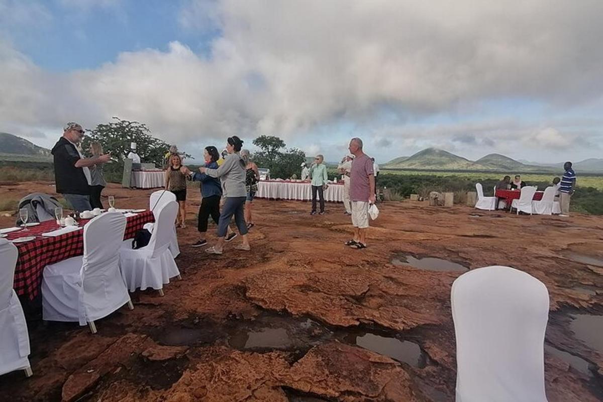 um grupo de pessoas em pé ao redor de mesas em um campo de terra