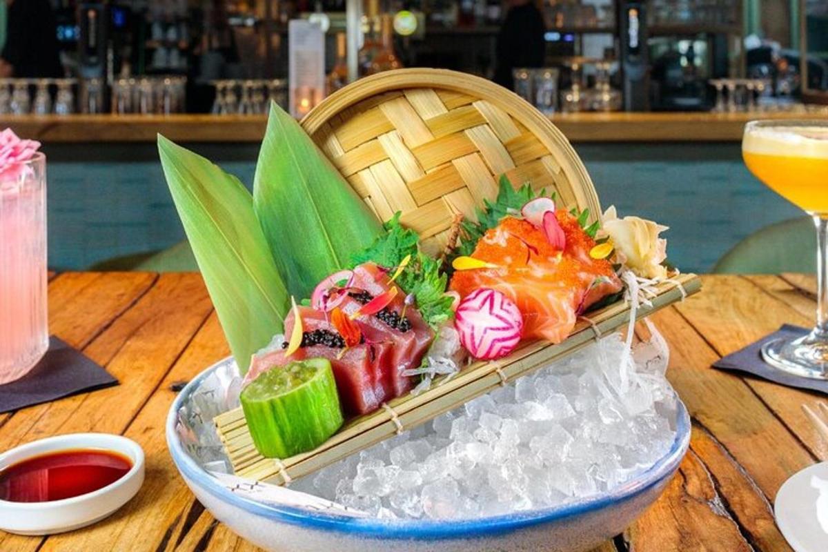 Una canasta de sushi en una mesa con una bebida.