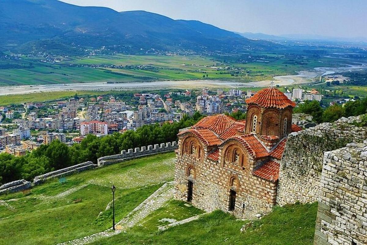 stavba na hribu z mestom v ozadju