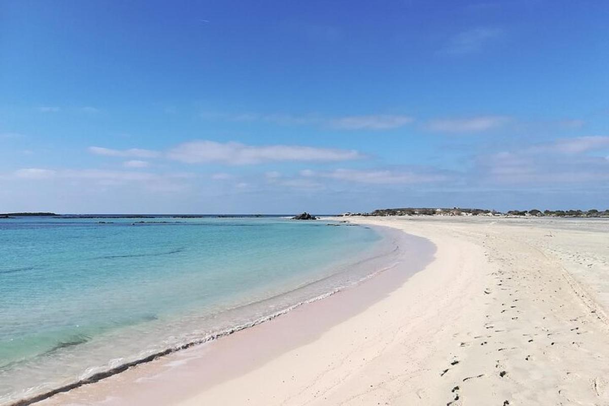 a beach with blue water and footprints in the sand