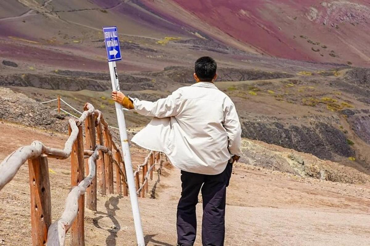 um homem parado ao lado de uma placa azul em uma montanha