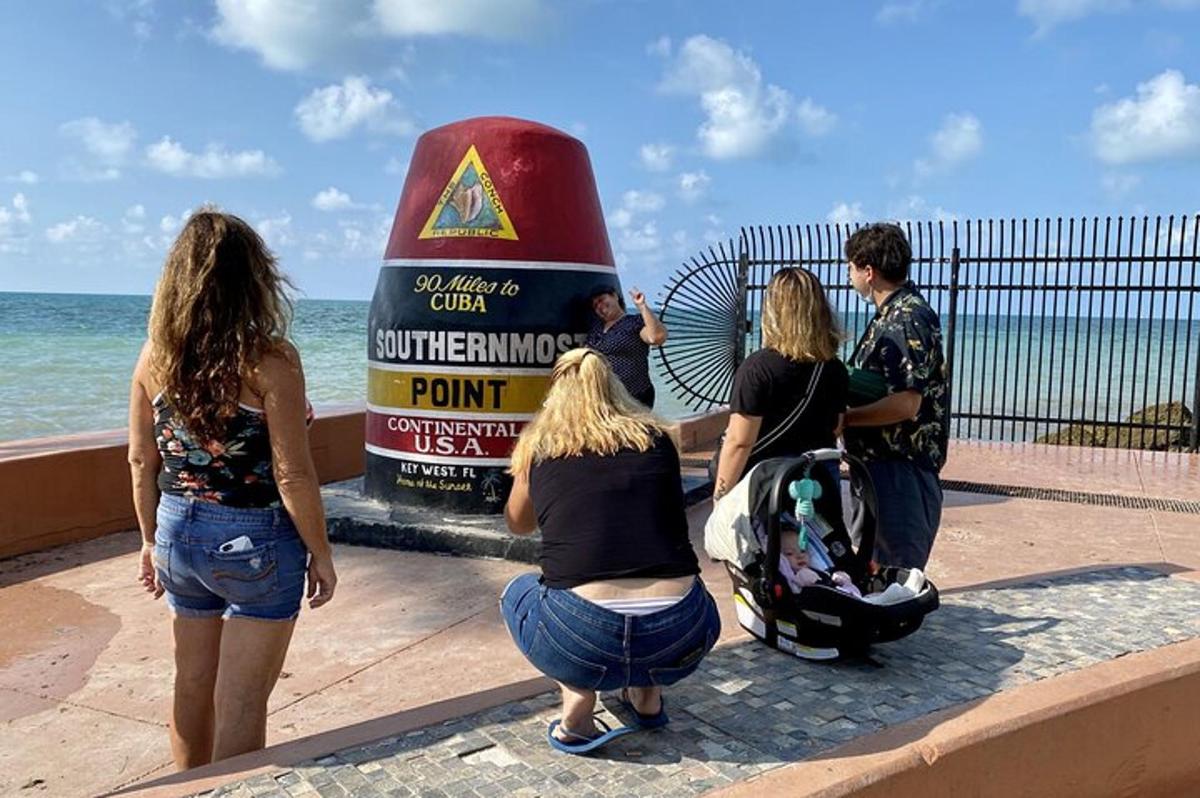 un gruppo di persone in piedi attorno a un cartello vicino all'oceano