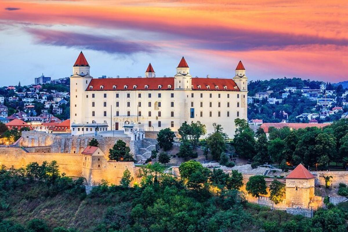 velik grad na vrhu hriba ob sončnem zahodu
