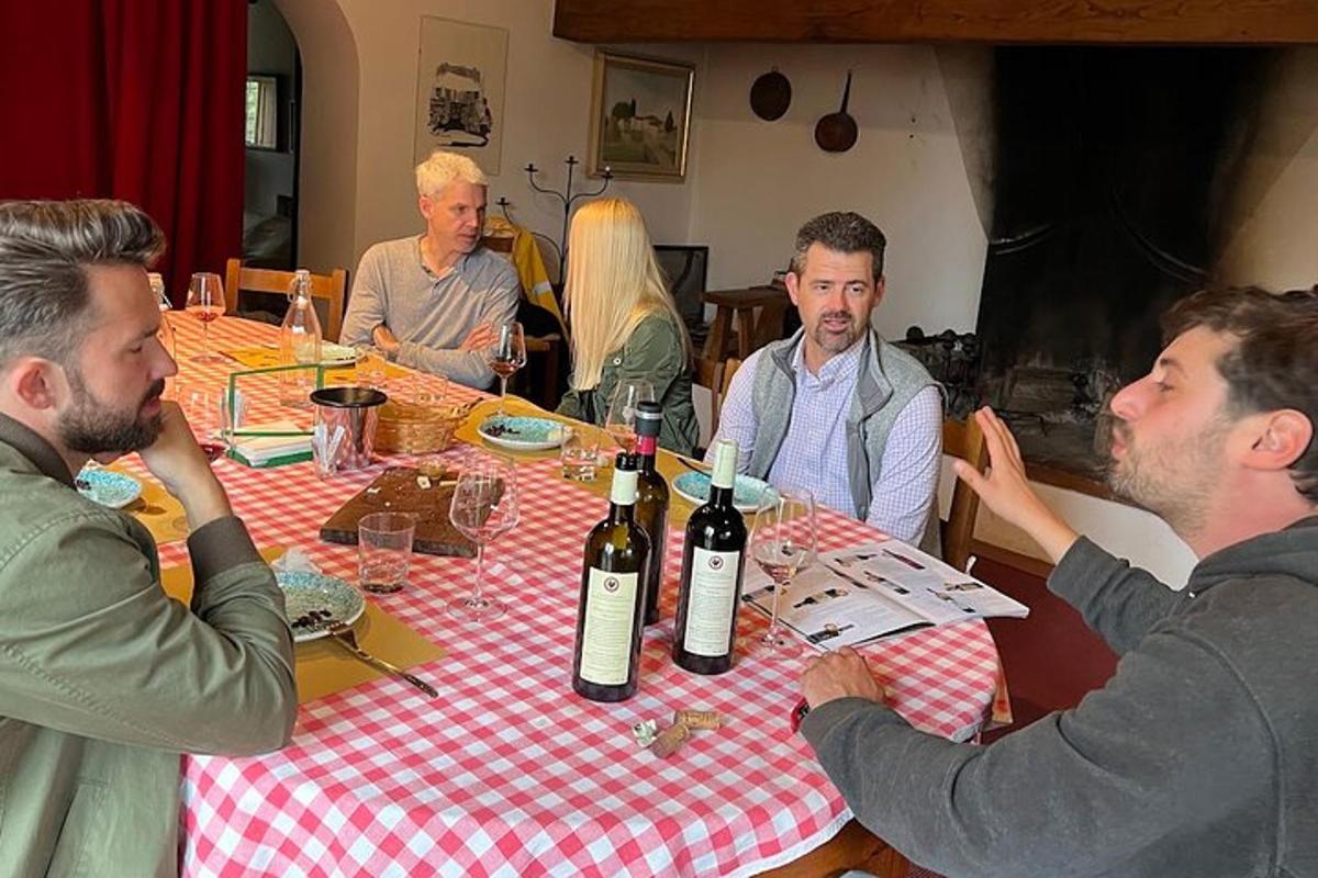 skupina lidí sedících kolem stolu s lahvemi vína