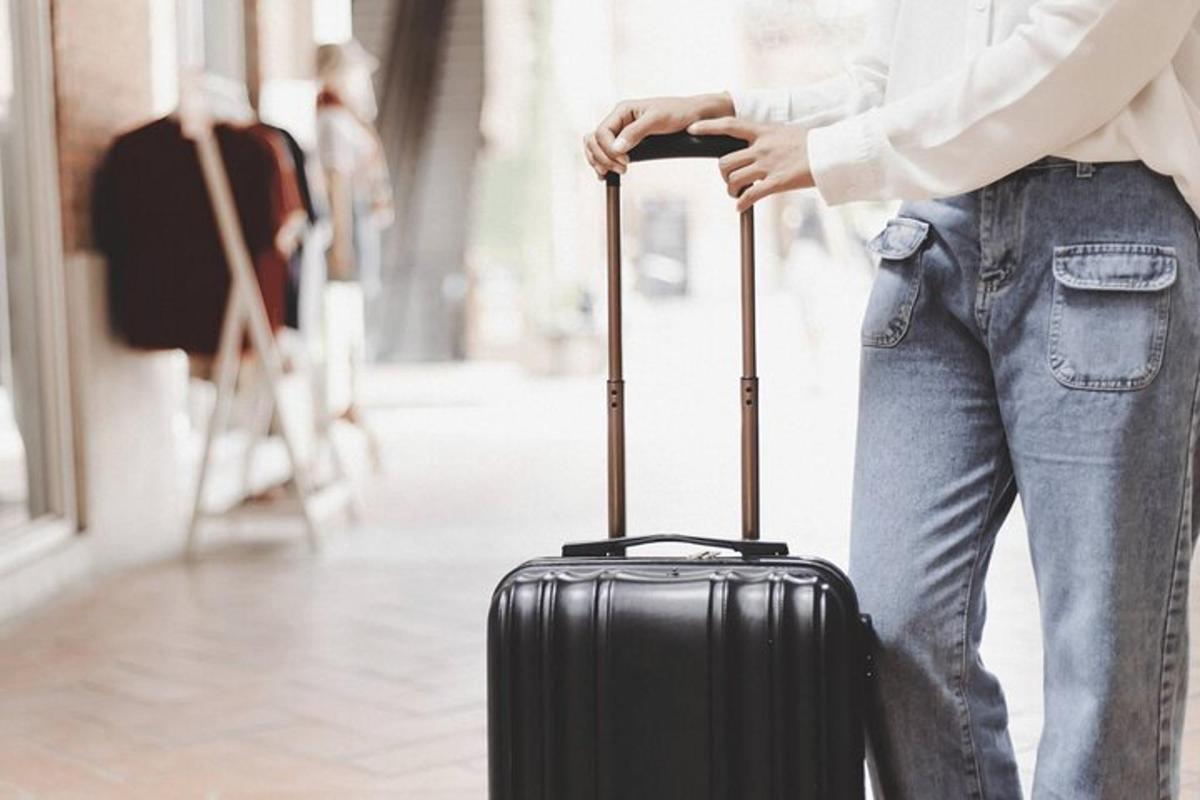 một người phụ nữ đang cầm một chiếc vali màu đen