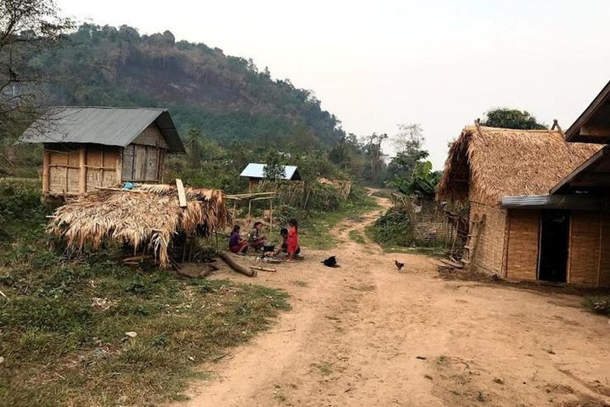 a group of people sitting on the side of a dirt road