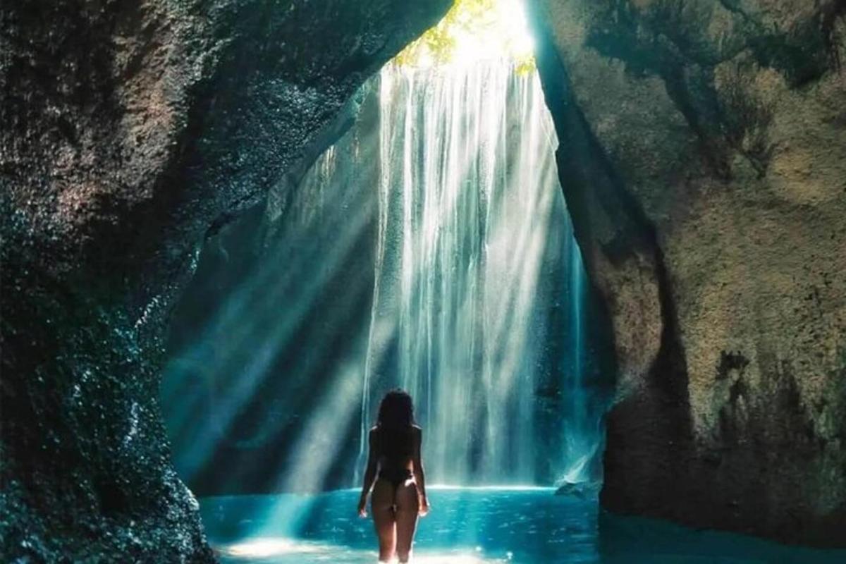 seorang wanita berdiri di hadapan air terjun