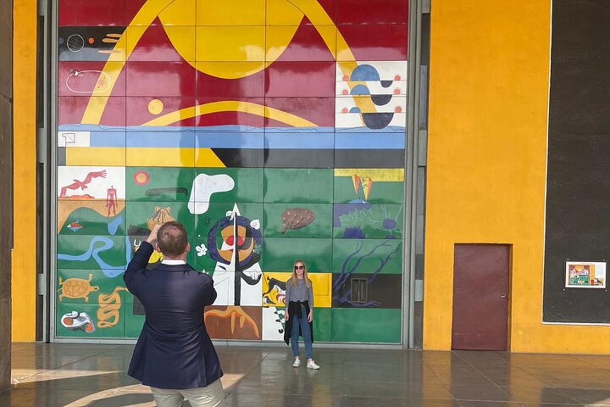 a woman taking a picture of a painting on a wall