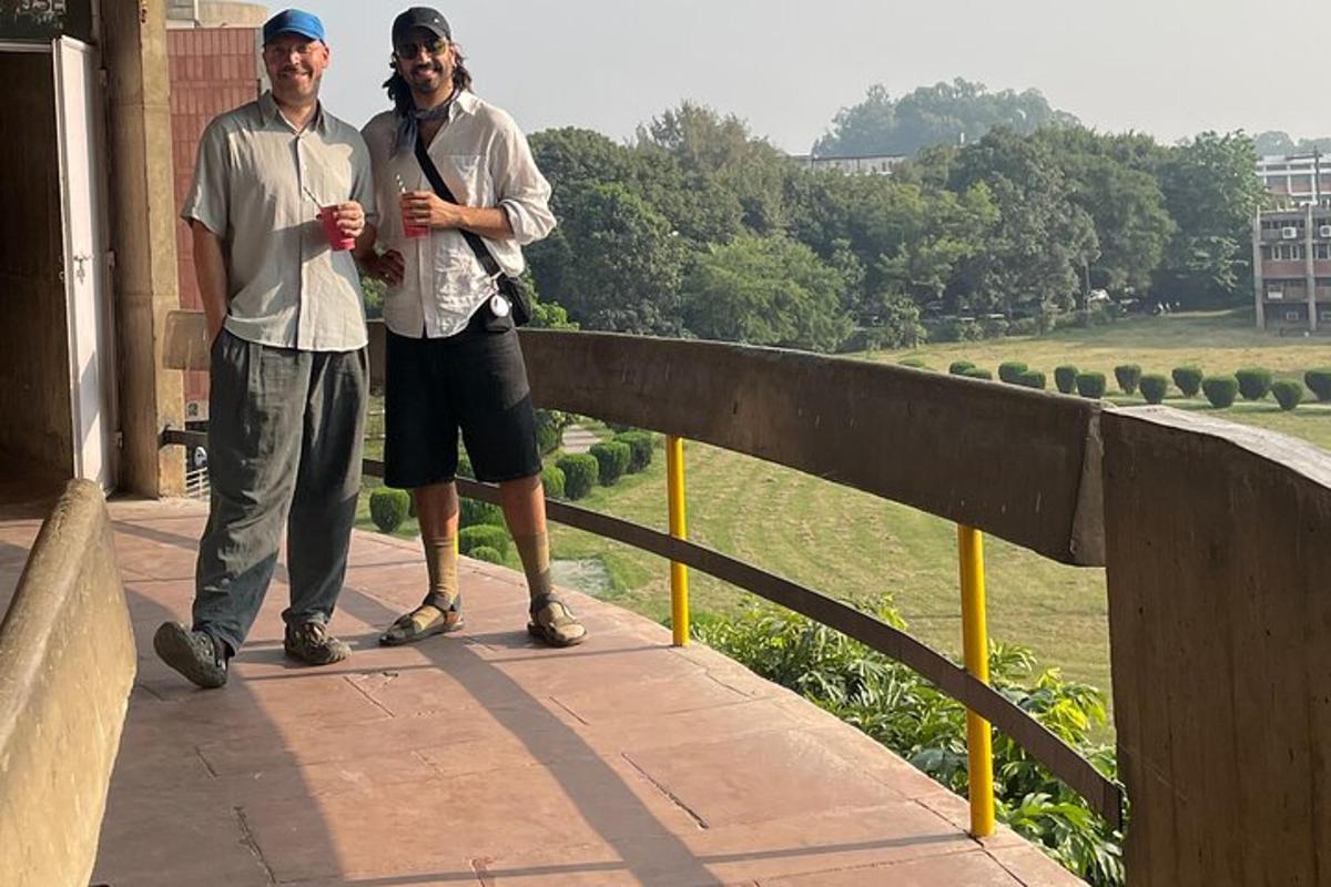 two men standing on a balcony looking out over a field