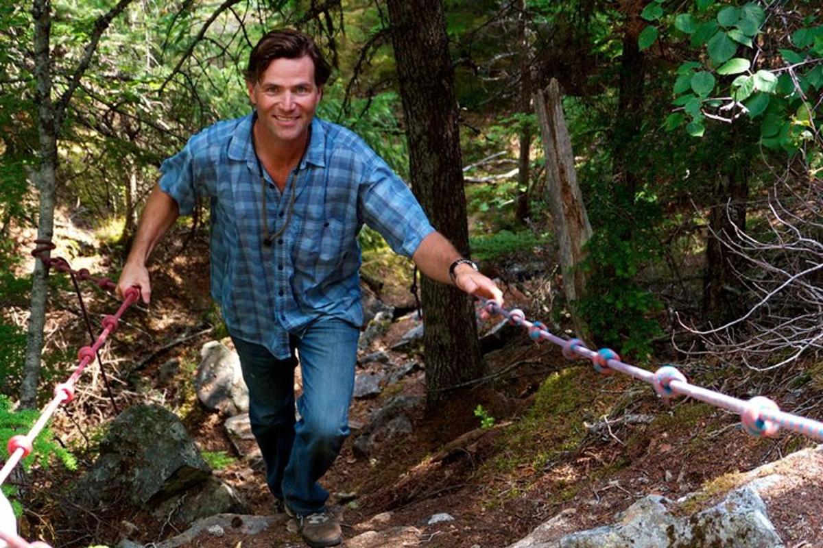 a man walking on a trail with a rope