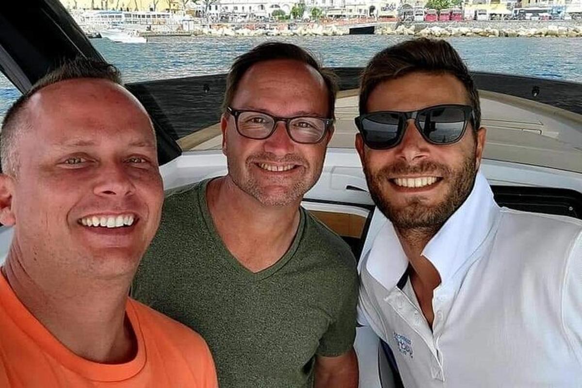 trois hommes posent pour une photo sur un bateau