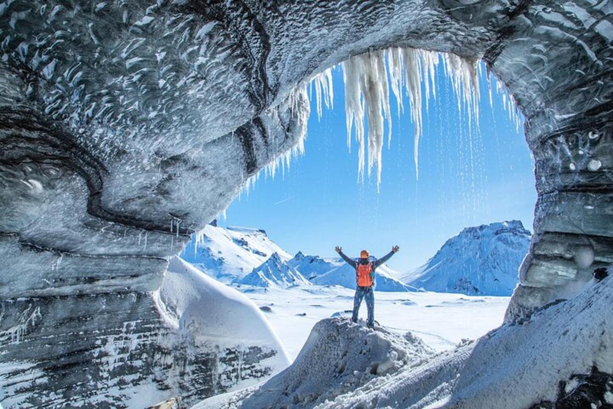 um homem parado em frente a uma caverna de gelo