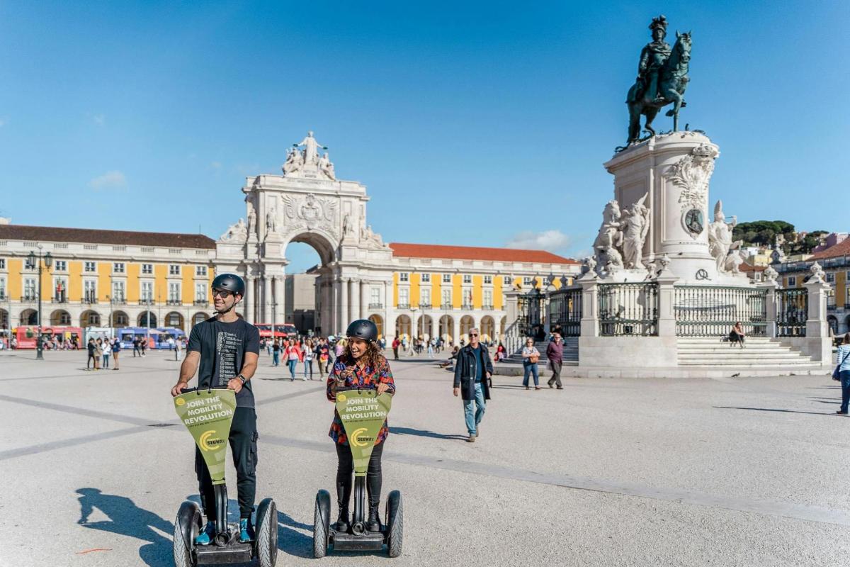 két ember segwayeken utazik egy épület előtt