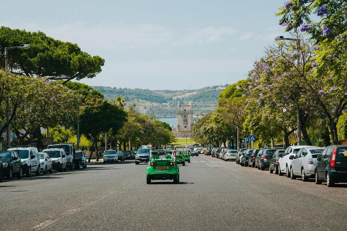 un golf cart verde che percorre una strada con auto parcheggiate