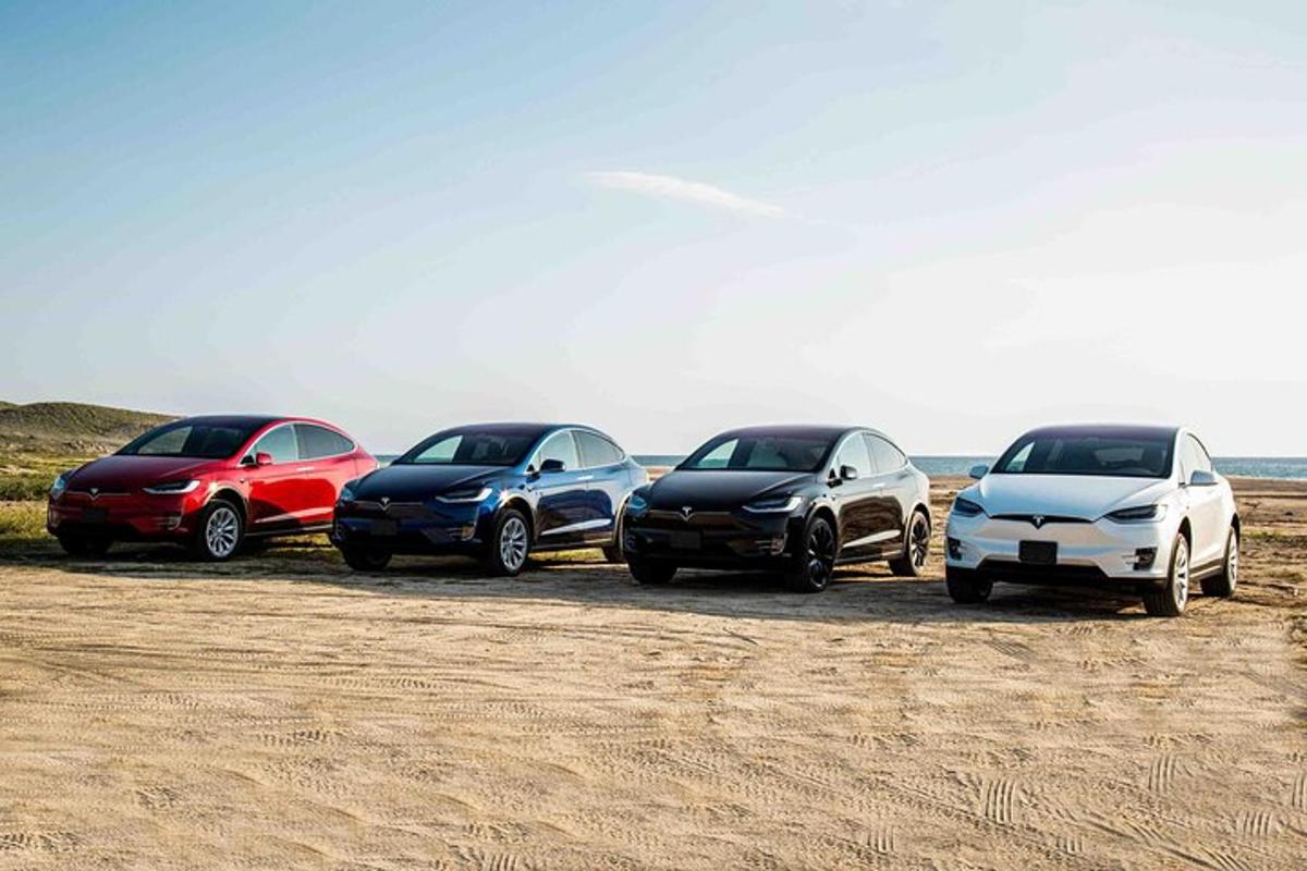 vier Autos in einer Reihe am Strand geparkt