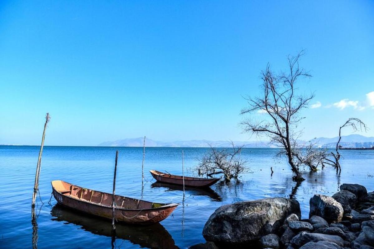 two boats sitting on the water near some rocks