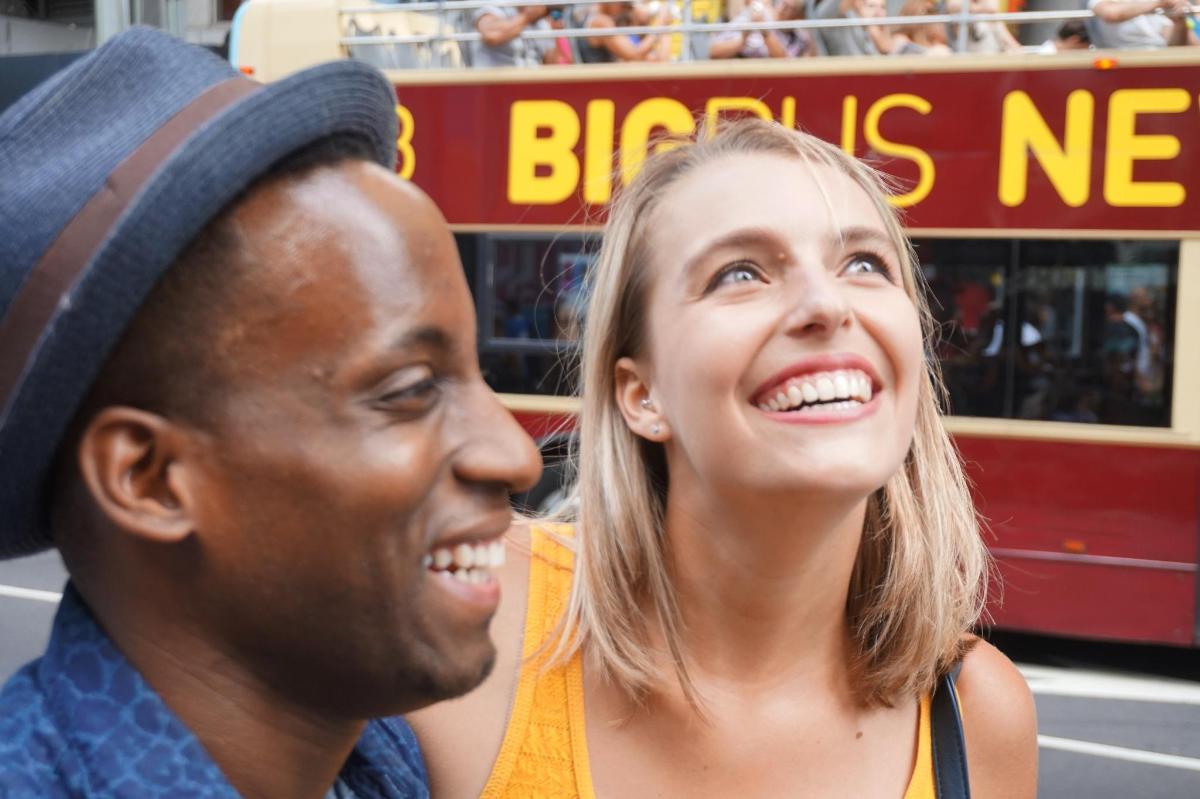 a man and a woman standing in front of a bus