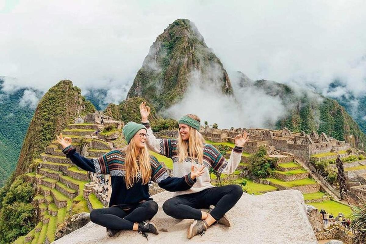 duas mulheres sentadas na beira de uma montanha