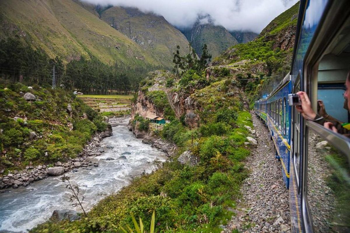 um trem viajando por um vale de montanha com um rio