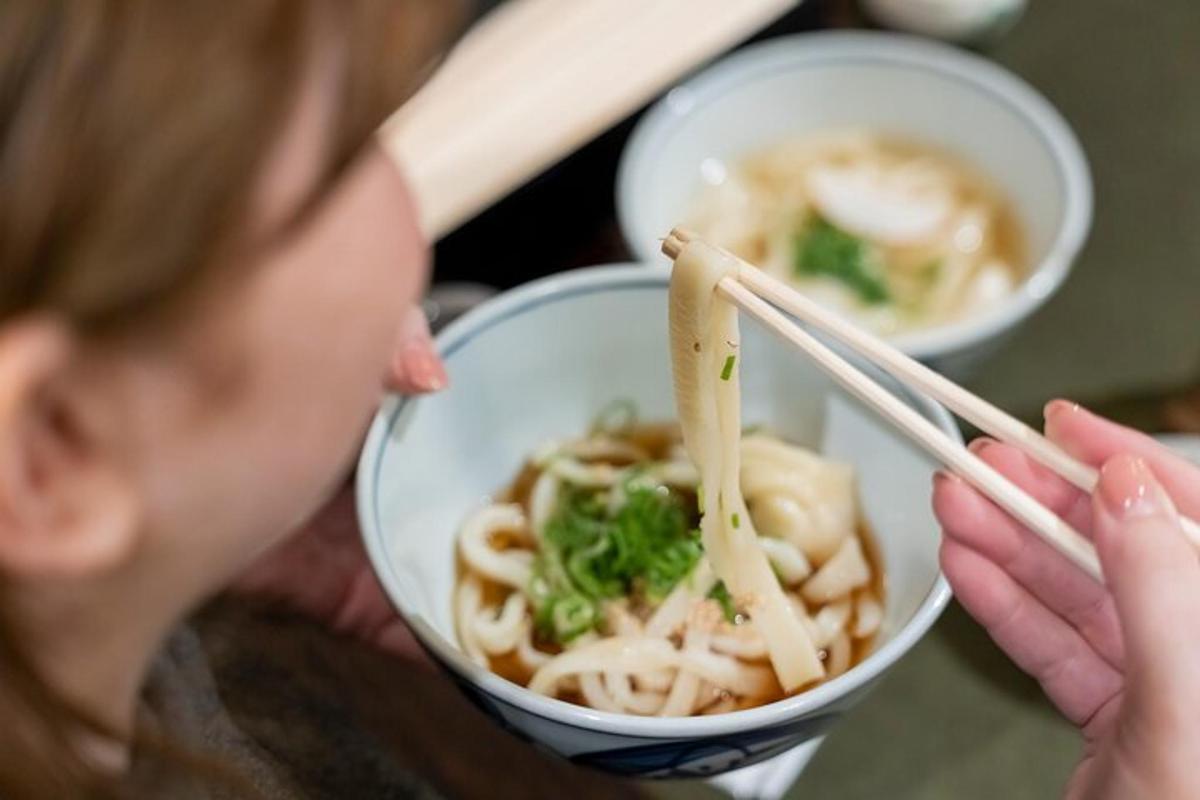 a woman is eating a bowl of noodles with chopsticks