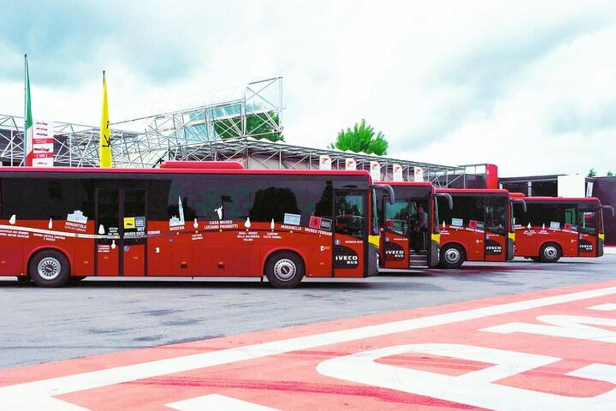 a row of red buses parked in a parking lot