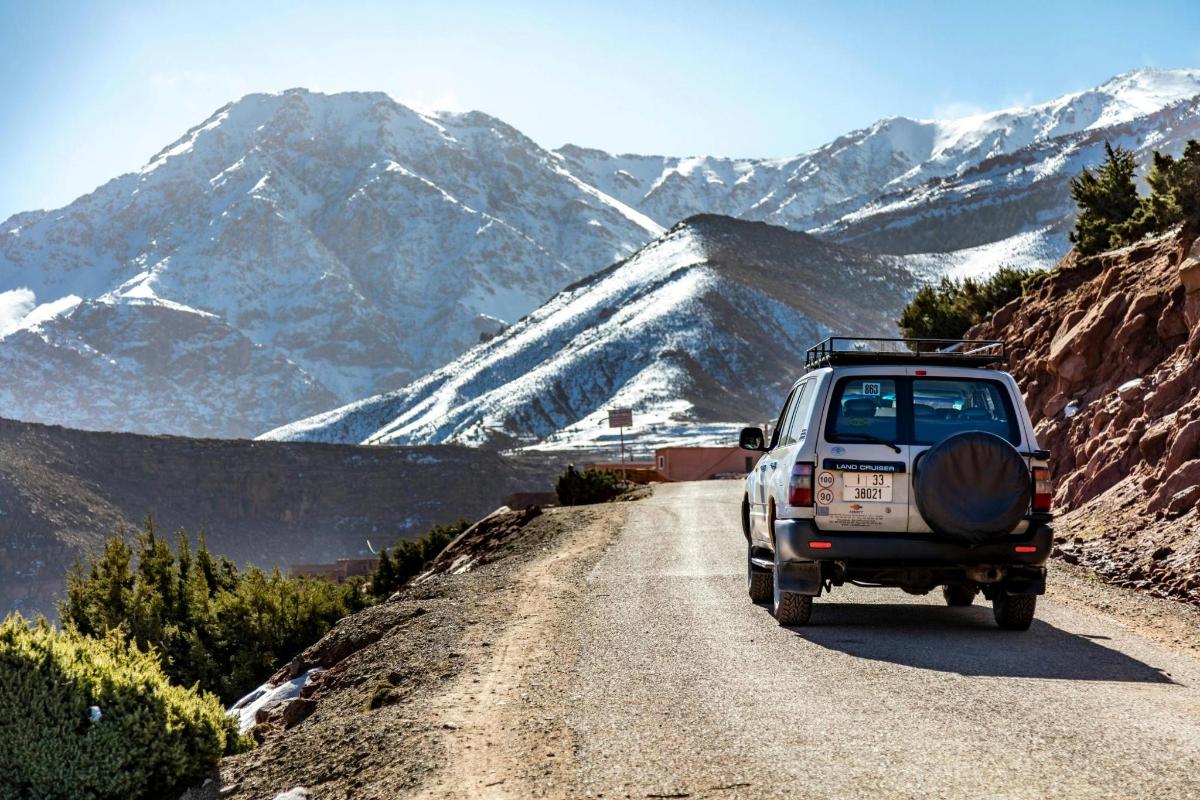 un camion roulant sur un chemin de terre avec des montagnes en arrière-plan