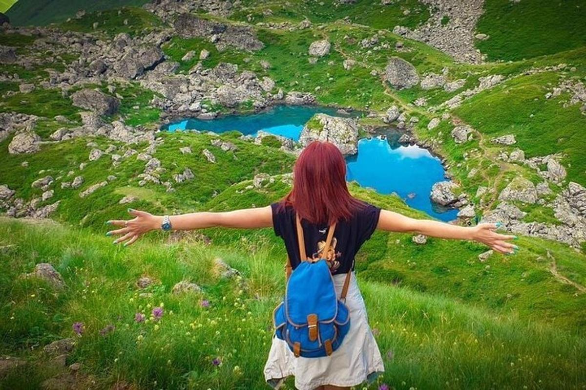 uma mulher com uma mochila azul em pé em uma colina com os braços abertos