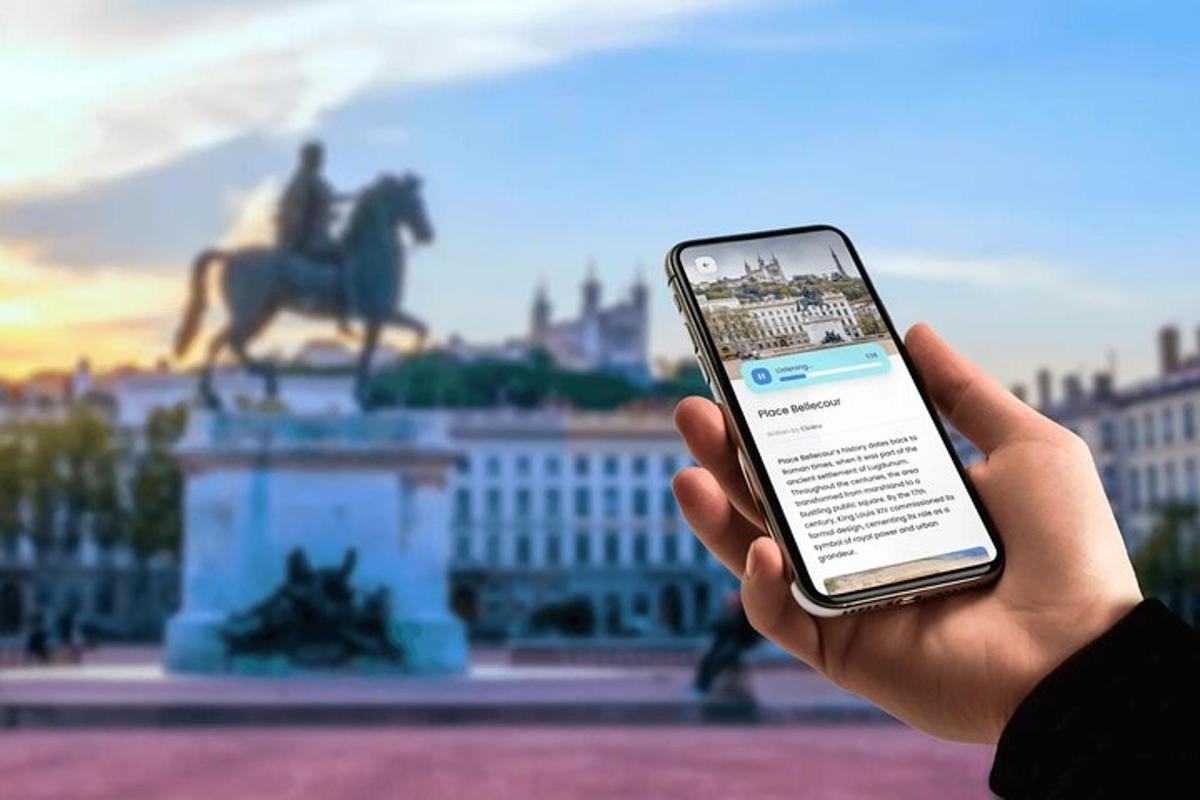 osoba držící mobilní telefon před sochou