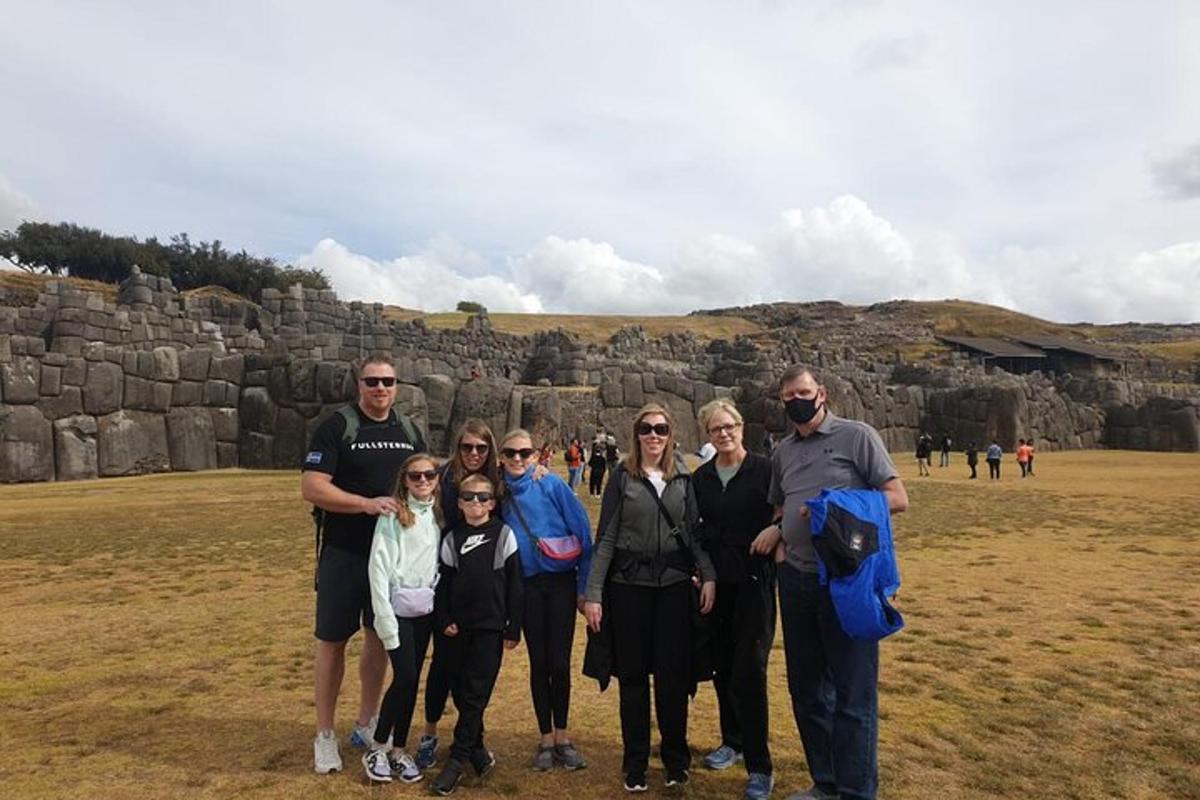 Un grupo de personas posando para una foto frente a un muro de piedra.