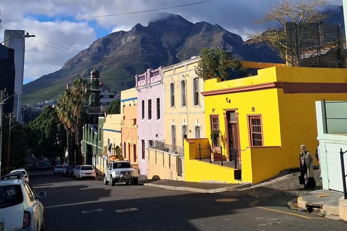 Una calle con edificios coloridos y una montaña al fondo.