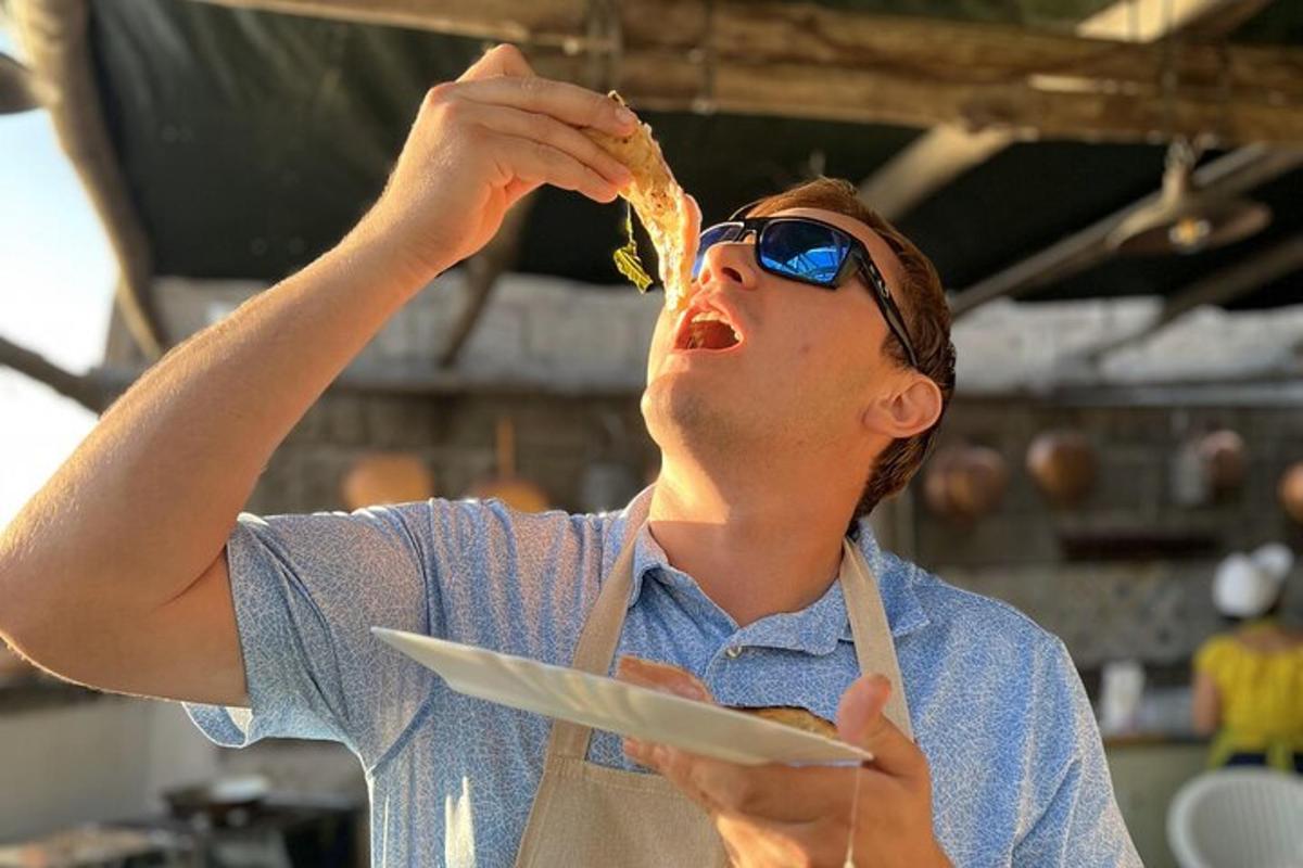 egy férfi napszemüvegben eszik egy szelet pizzát