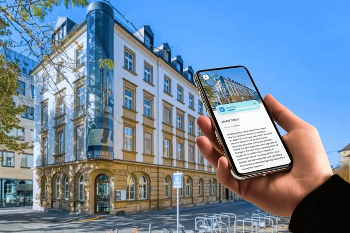 osoba držící mobilní telefon před budovou