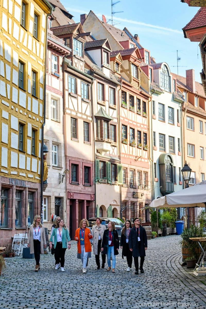a group of people walking down a street with buildings