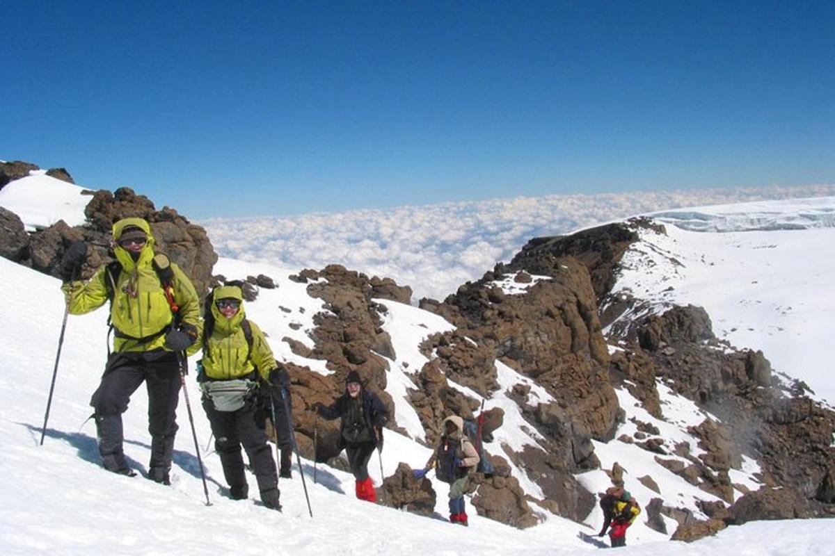 sekumpulan orang berdiri di atas gunung yang dilitupi salji