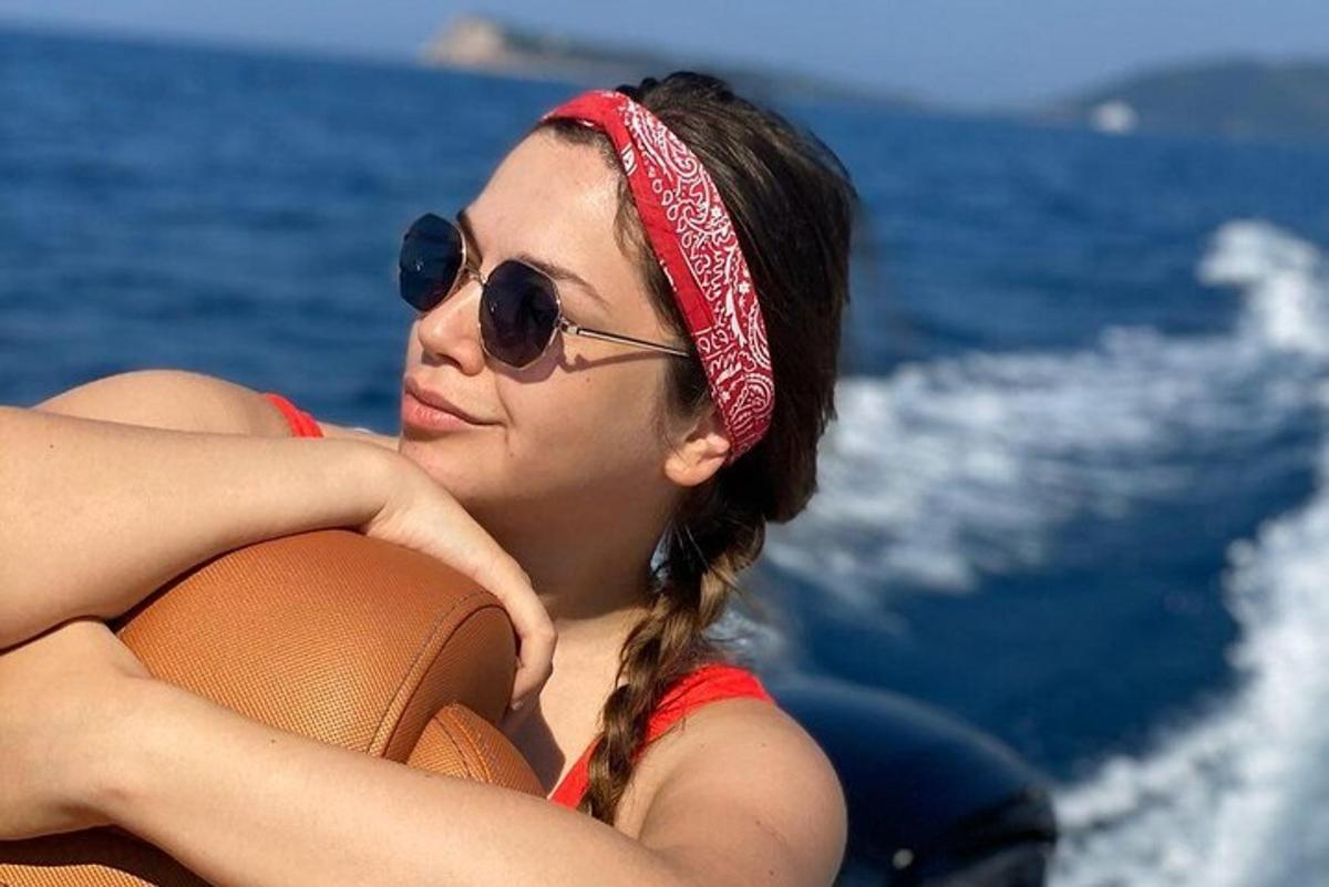Μια γυναίκα που φοράει γυαλιά ηλίου και κόκκινη κορδέλα για τα μαλλιά ξαπλωμένη σε μια βάρκα
