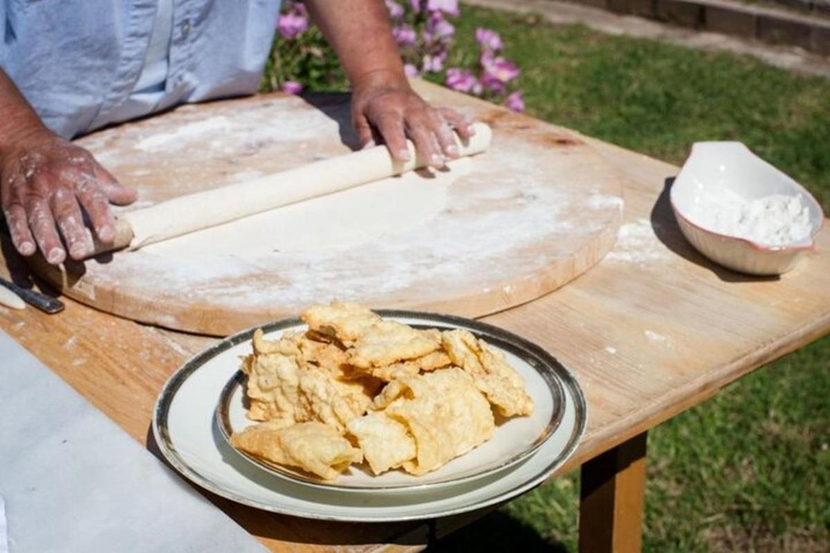 una persona que fa rodar massa sobre una taula amb un plat de menjar