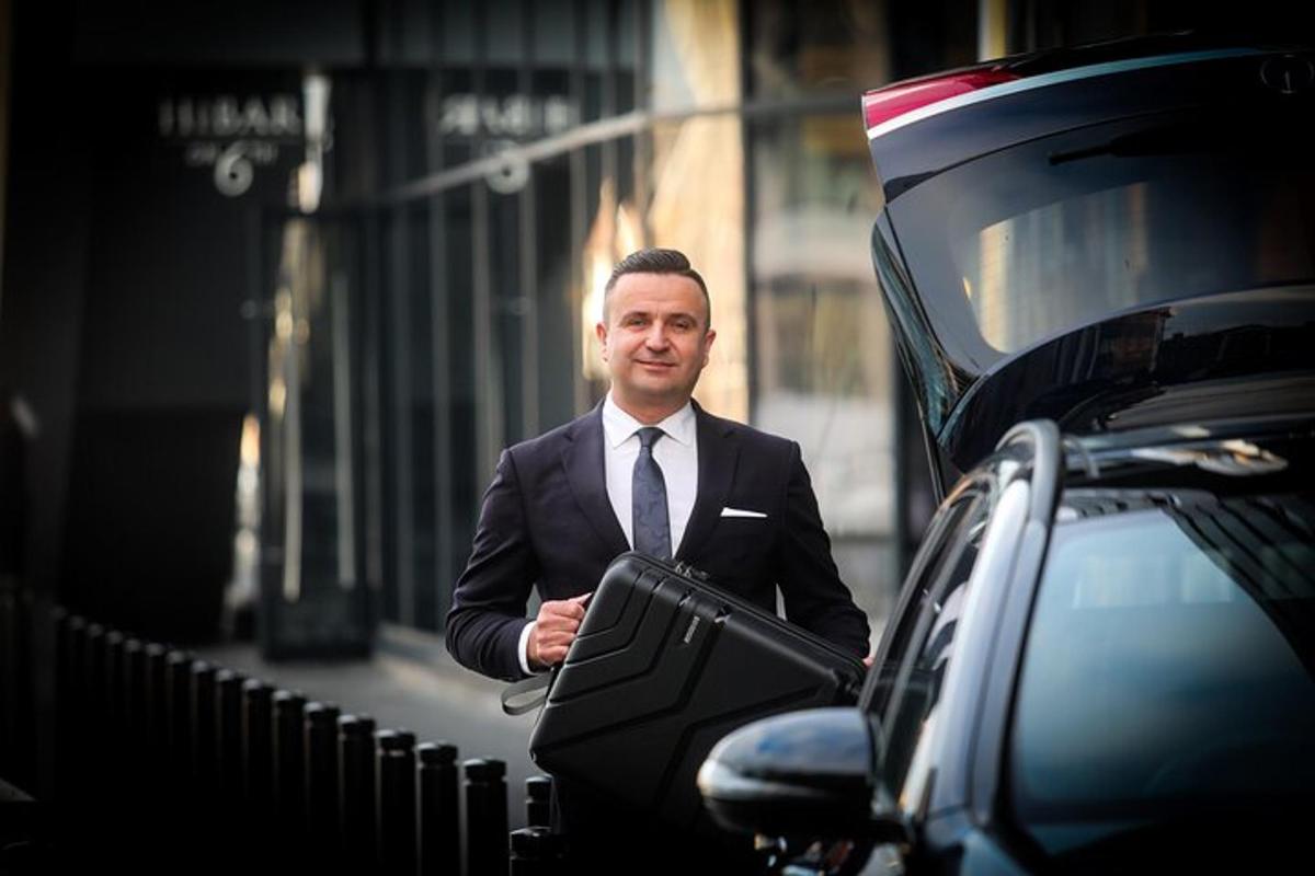 a man in a suit and tie standing next to a car