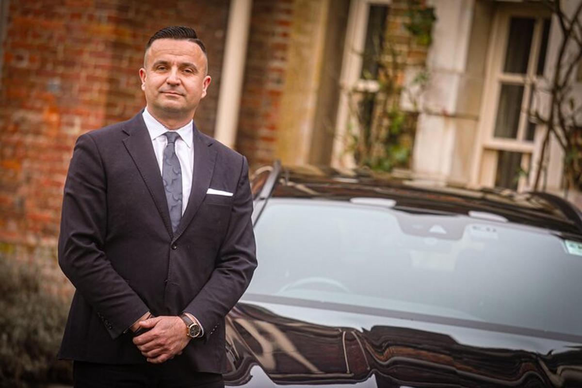 a man in a suit standing in front of a car
