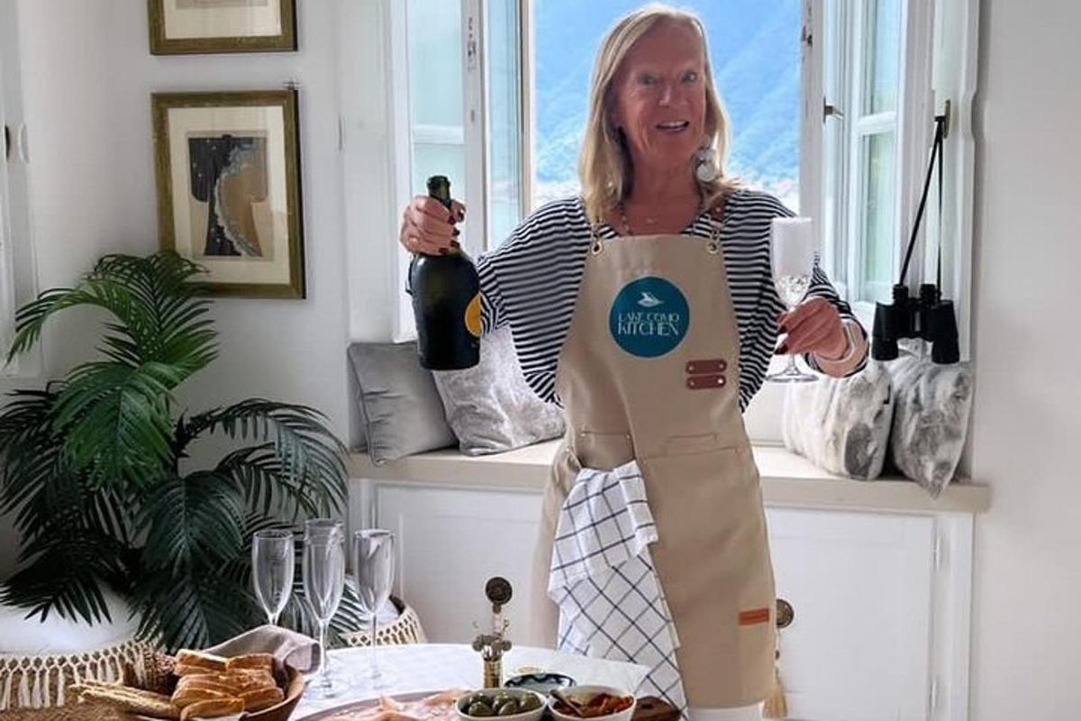 una donna con il grembiule che tiene in mano una bottiglia di vino