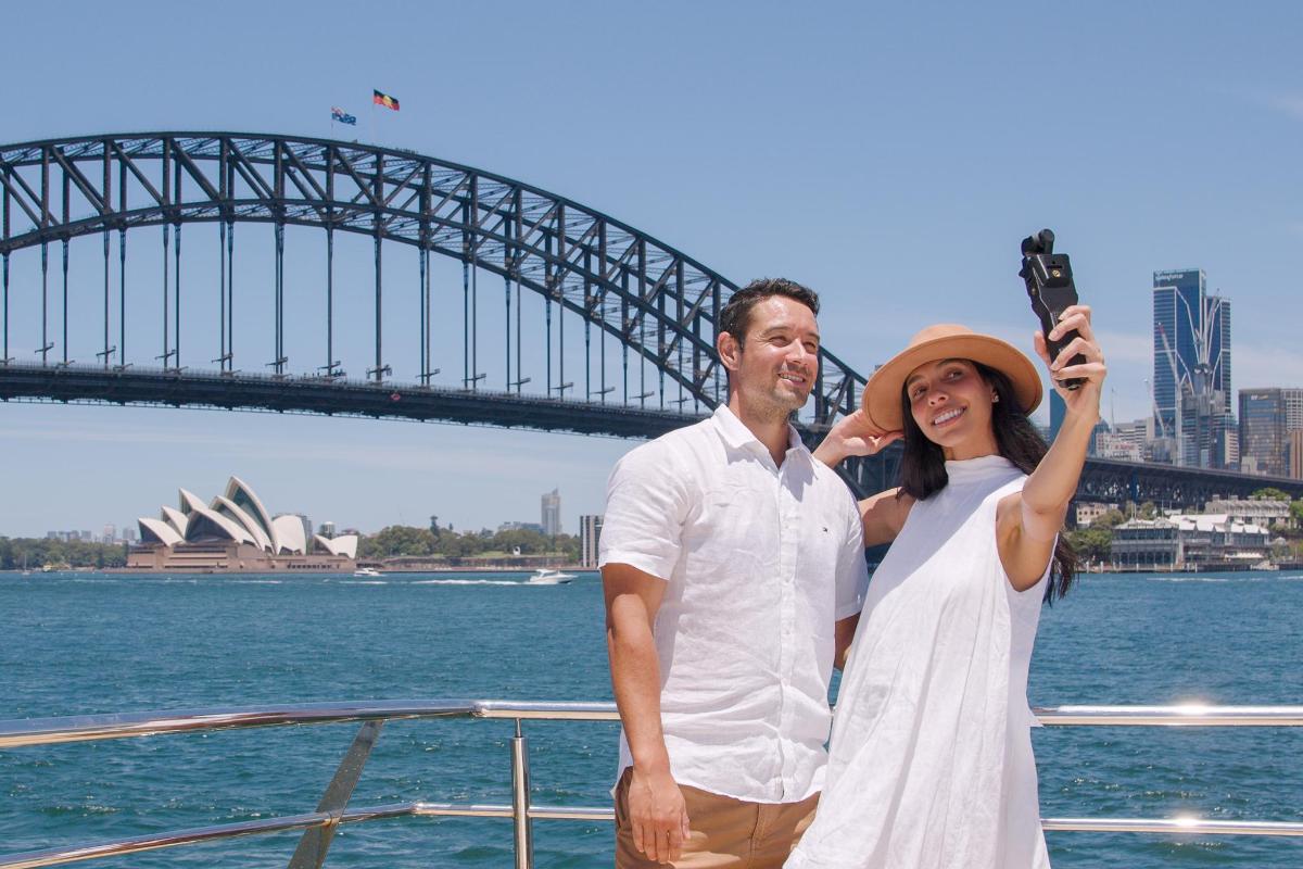 a man and woman standing on a boat in front of a bridge