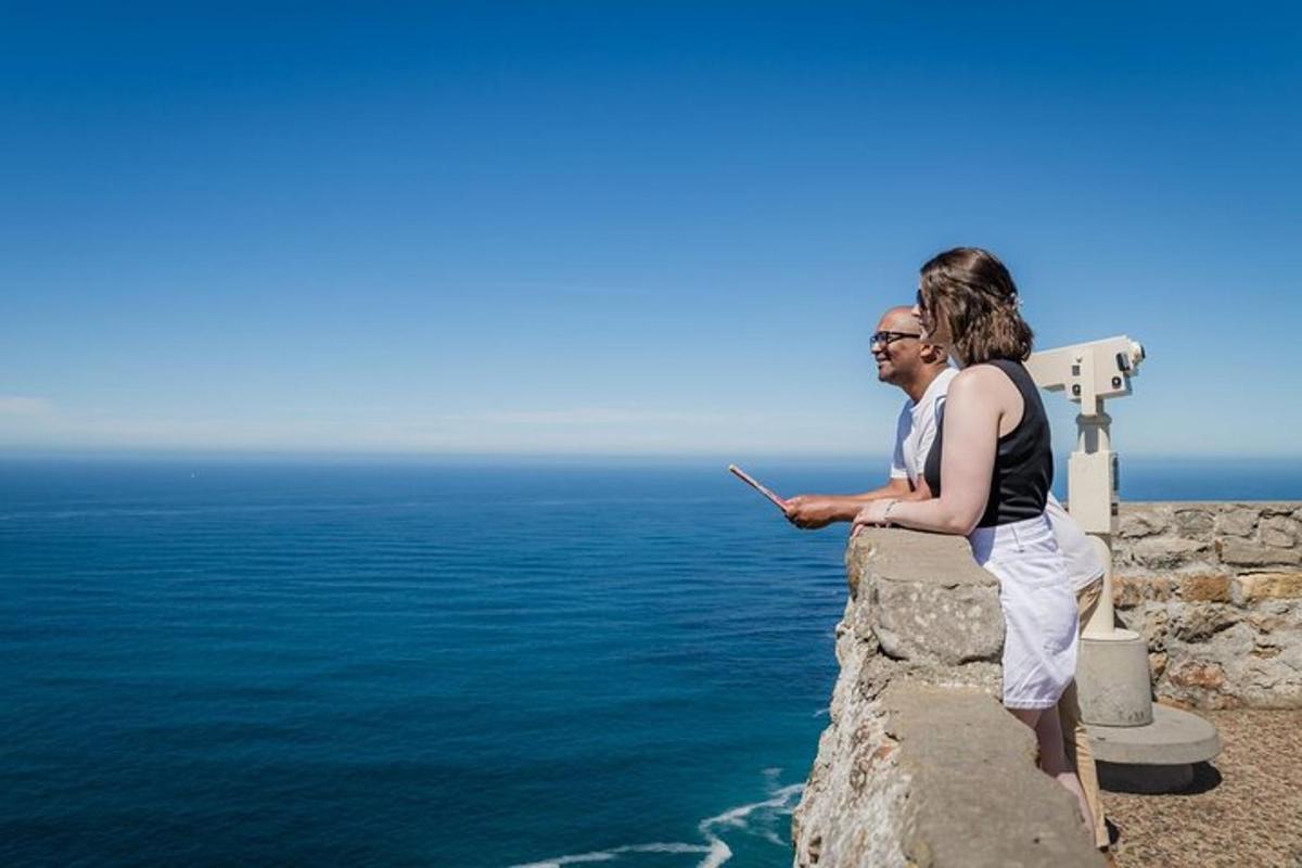 Un hombre y una mujer de pie en un muro con vistas al océano.