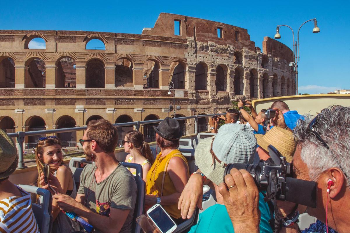 a group of people riding on a bus in front of the coliseum