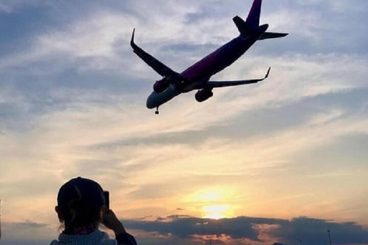 a person taking a picture of an airplane in the sky