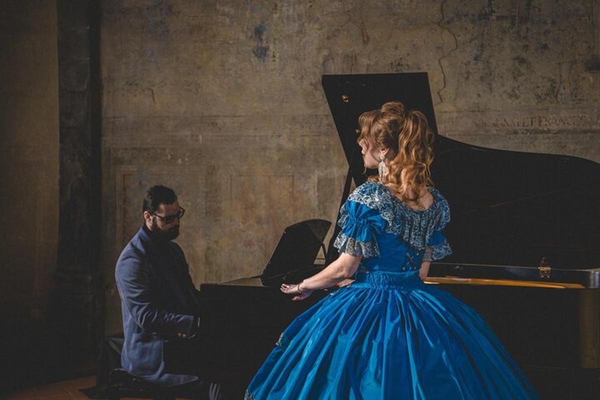 una dona amb un vestit blau dempeus al costat d'un piano