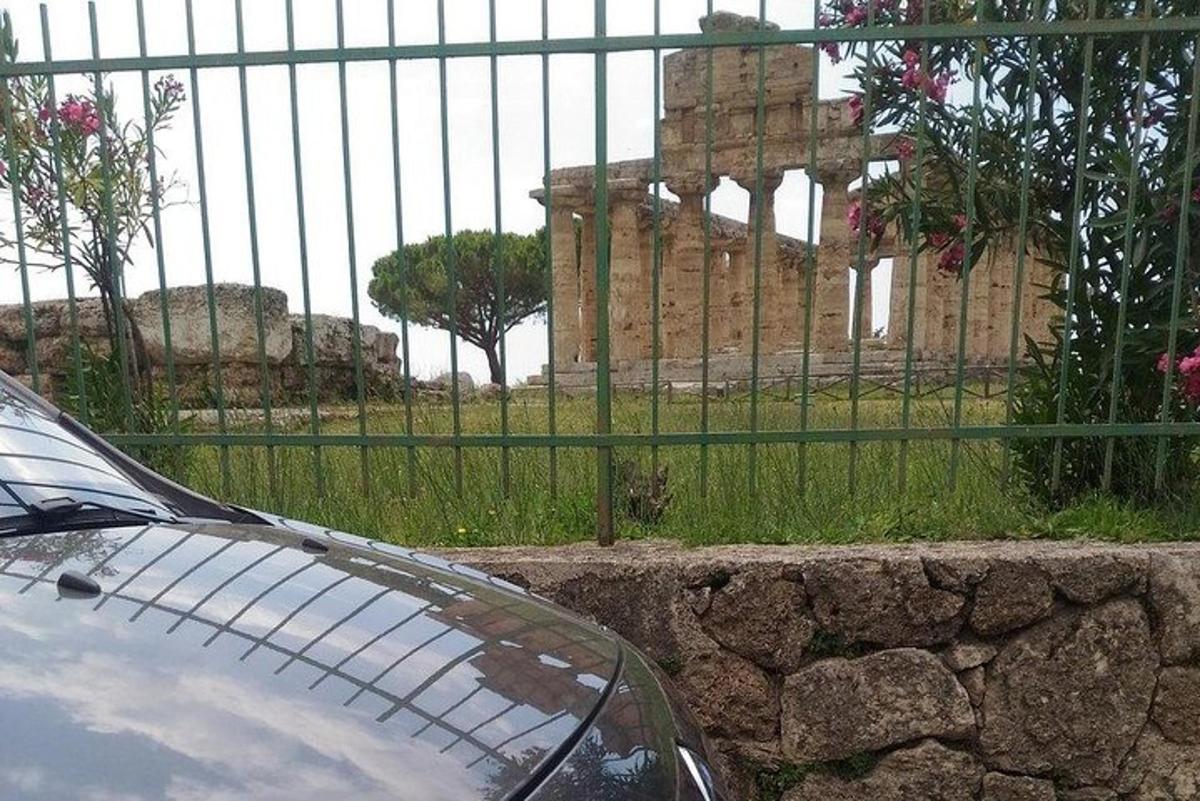 Un coche aparcado delante de una valla delante de un edificio.