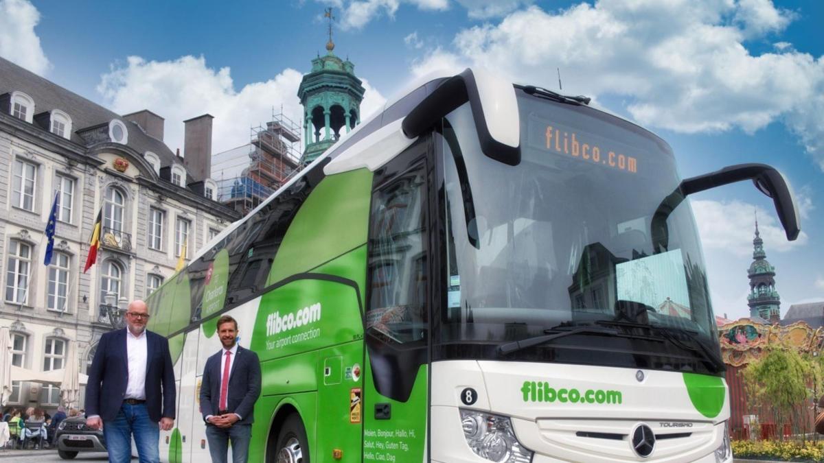 Dos hombres de pie junto a un autobús verde y blanco.